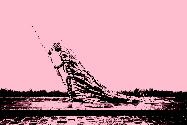 This image depicts a person wearing a long cape adorned with wooden statuettes walking along the cobbled sidewalk of a damp street. Under the cape, a white painted grid covers his body and he strides forward laboriously with the help of a large sculpted scepter.