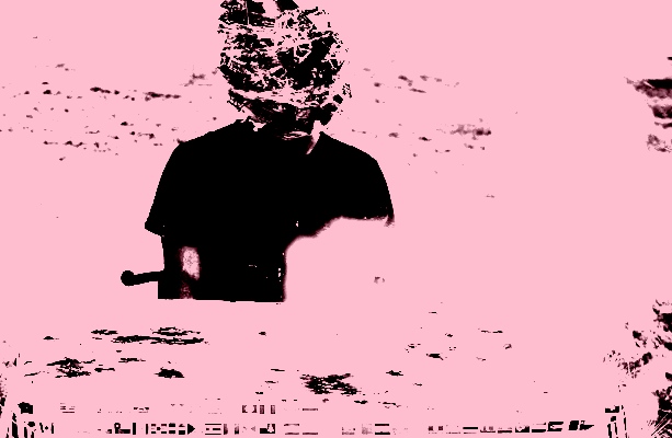 This image depicts hundreds of plastic toy soldiers taped to the head of a person sitting at a table that is placed outdoors. On the table, firecrackers explode on a map of the world leaving behind violent burn marks.